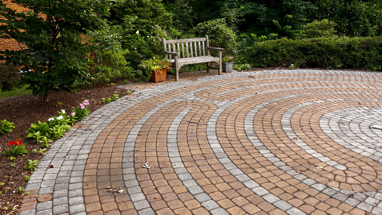 brick pavers near grass and a wood bench