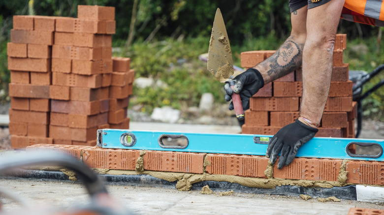 A person building a brick wall