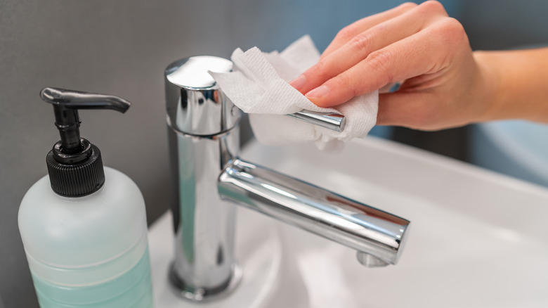 person shining faucet with paper