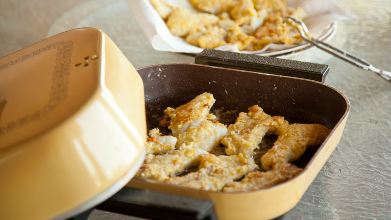 Vintage electric skillet containing battered fish
