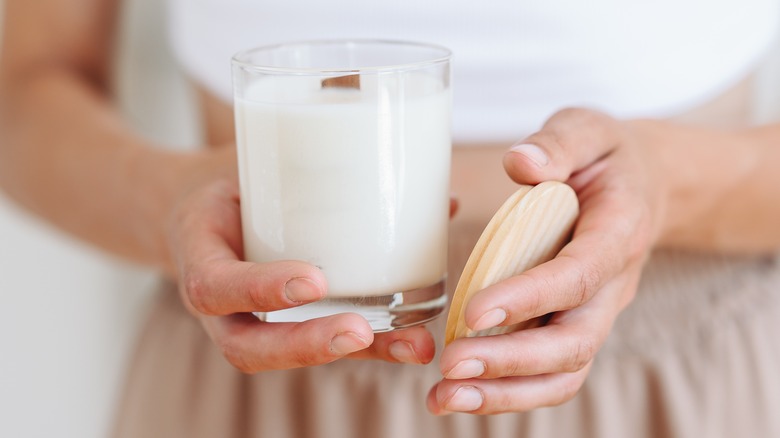 Person holding candle jar and lid