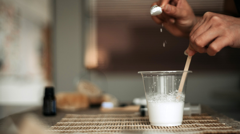 A person makes a cleaning paste using baking soda and dish soap.
