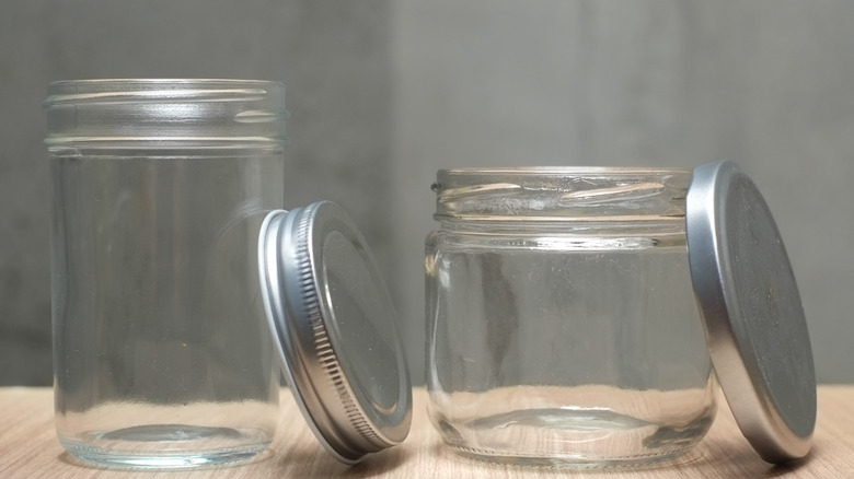 Two clear Mason jars sitting near each other, the tops are leaning on the right side of the jars