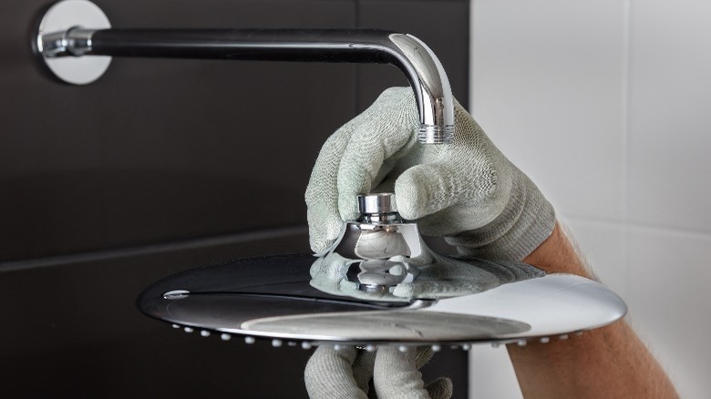 person with gloves removing shower head