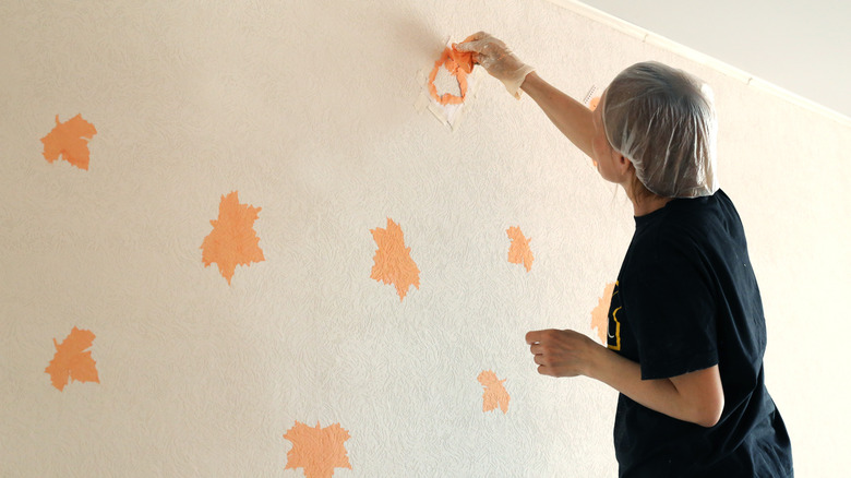 Woman adding paint design to wall using tape stencil