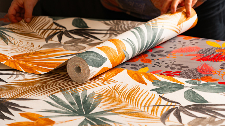 Someone rolling out leafy wallpaper