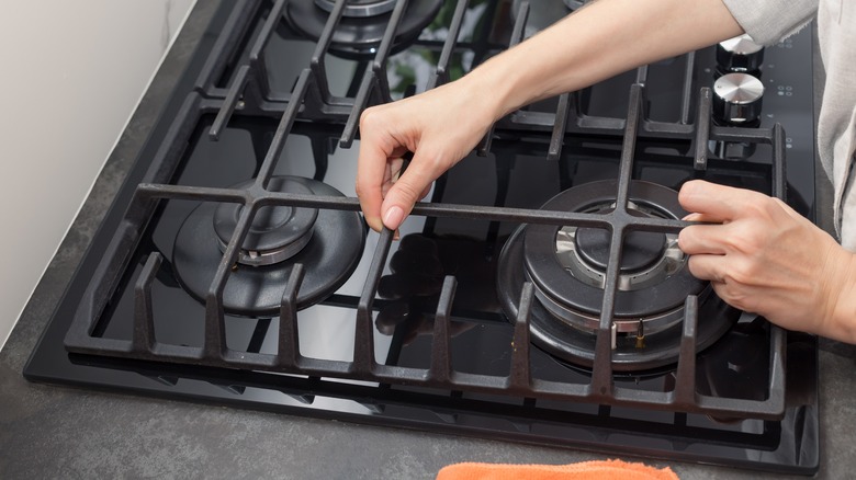 person lifting stovetop iron grates