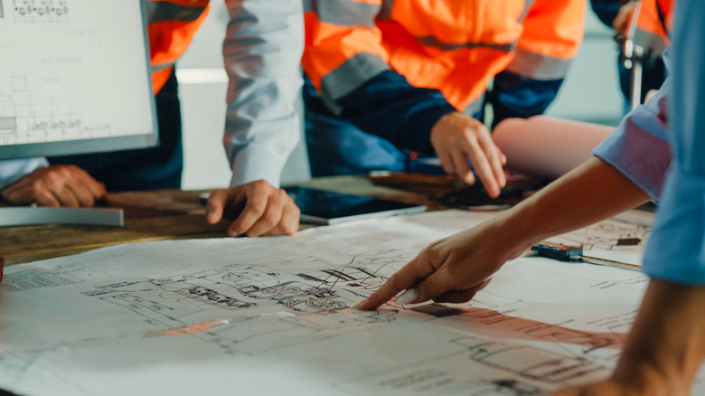 woman pointing at paper blueprints
