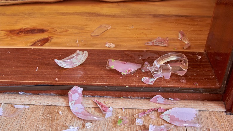 Pieces of a broken glass cup on wooden flooring