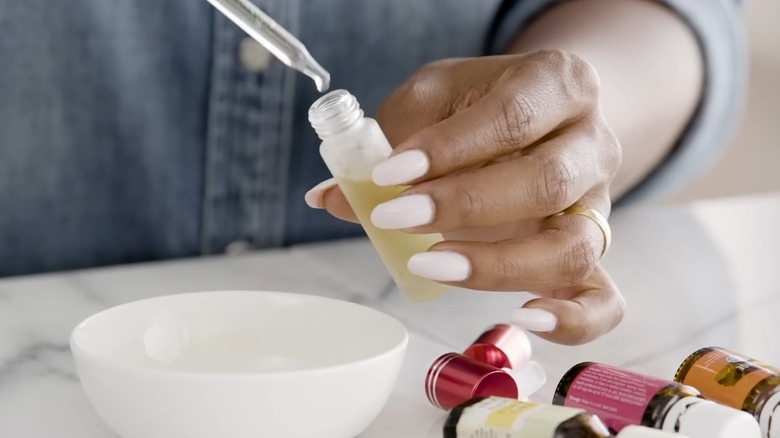 Hands filling a small perfume bottle with a dropper