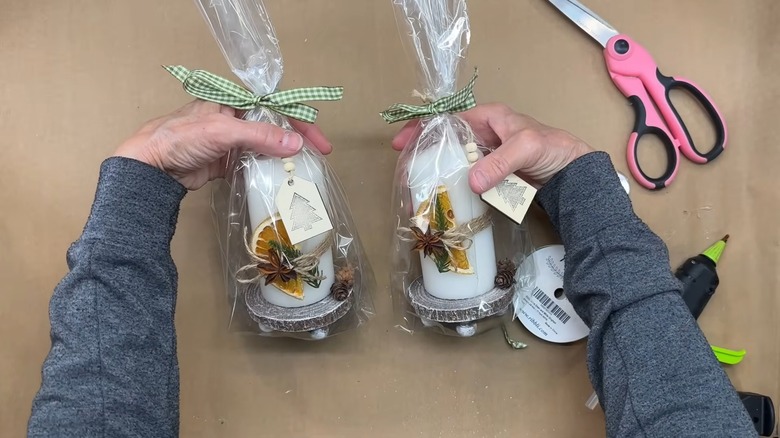 Hands holding two white Christmas pillar candles