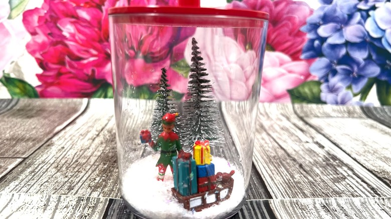 A snow globe with miniature holiday decorations in a jar