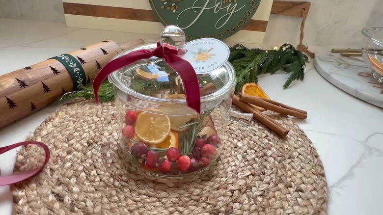 A glass simmer pot holding dried fruit on a table