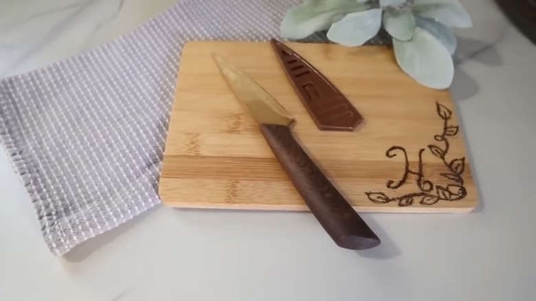 A bamboo cutting board with knife on top