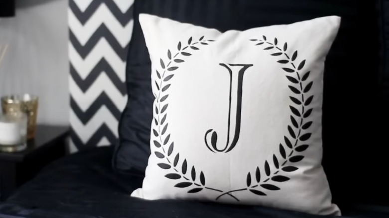 A white throw pillow with a J initialed on it