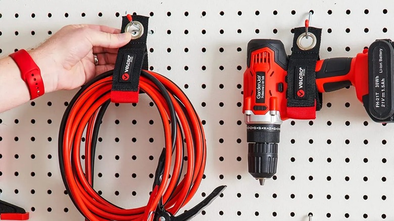 Velcro Brand Easy Hang Extension Cord Holder holding extension cord and cordless drill on pegboard wall