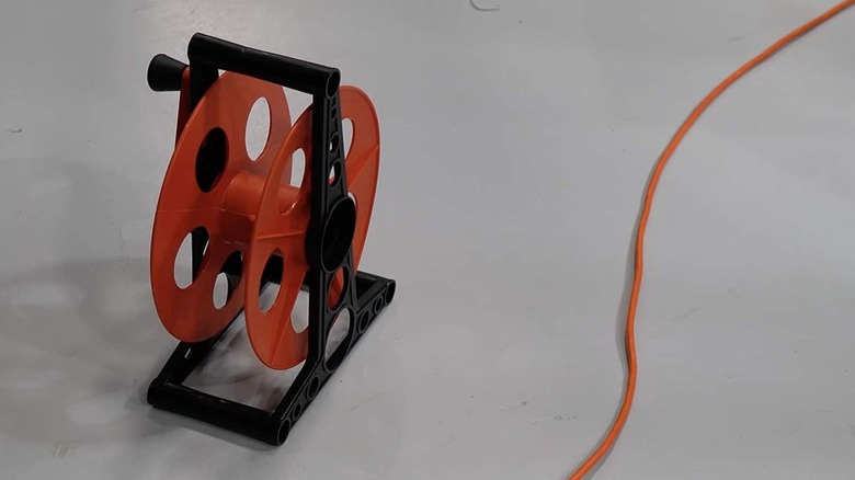 Woods Extension Cord Storage Reel on floor next to extension cord