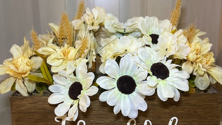 A wood flower box containing various types of artificial florals