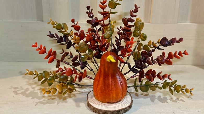 A foam turkey with eucalyptus feathers on a wood round