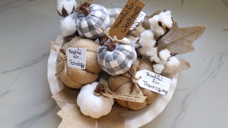 Small pumpkins with thankful notes inside a white bowl
