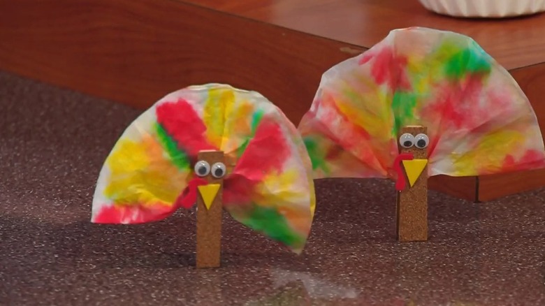 A colorful turkey place setting made out of clothespin and coffee filter