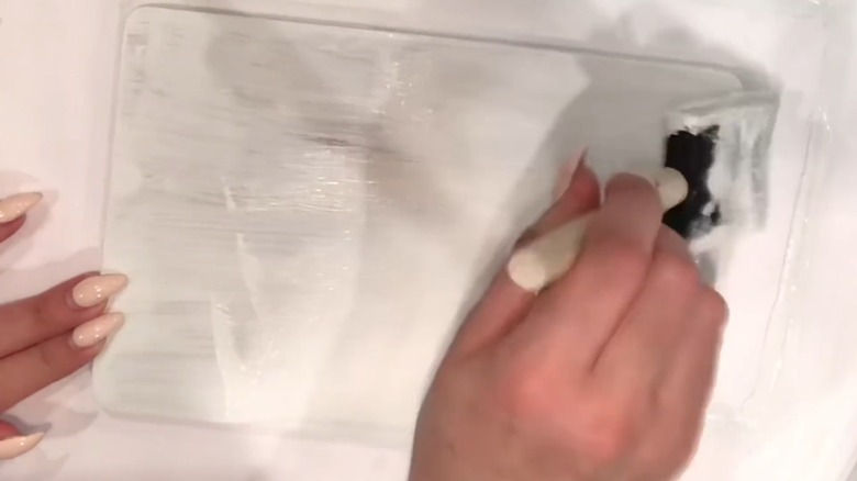 Hand painting a cutting board white using a foam brush