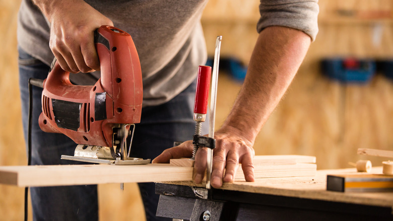 A man cutting a wooden board with a jigsaw