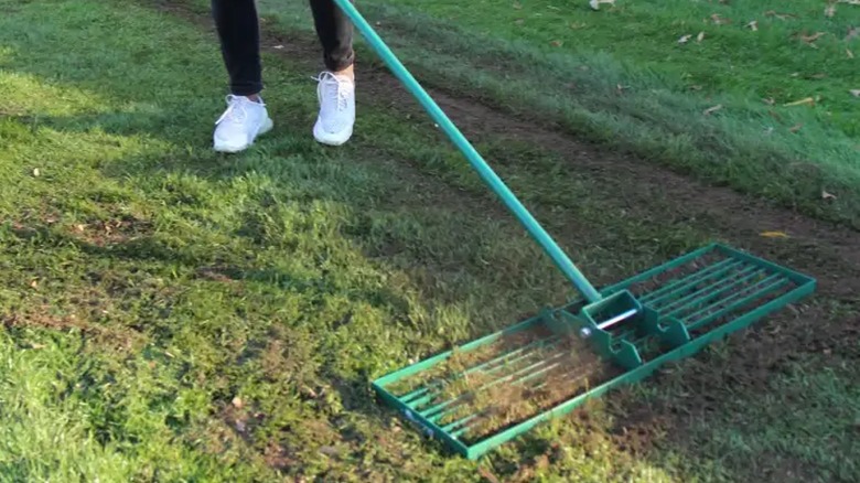 person using lawn leveling rake outdoors