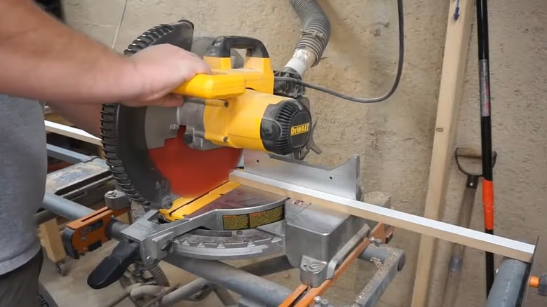 A person cutting a piece of wood to build shelves