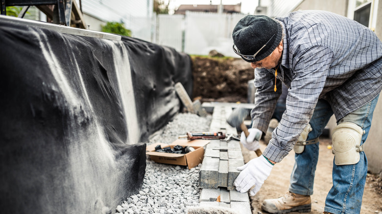 a senior man building a retaining wall with landscape fabric