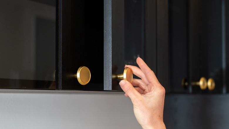Black cabinet door being opened slightly  