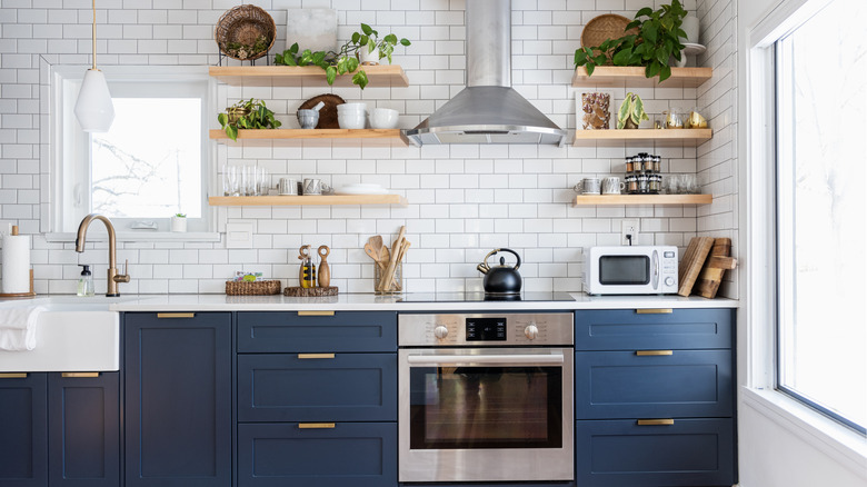 A kitchen with blue cabinets and brass hardware