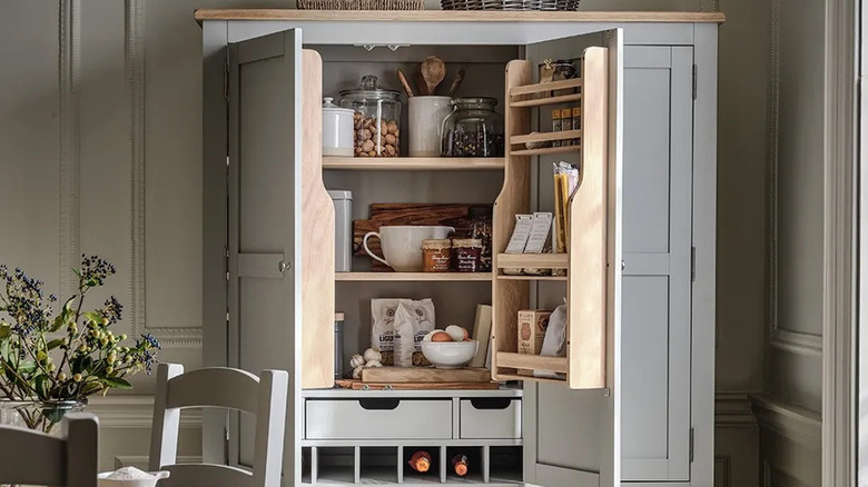 A light gray open kitchen cupboard with ingredients and dishes inside
