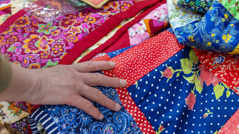 close up of a person touching quilts