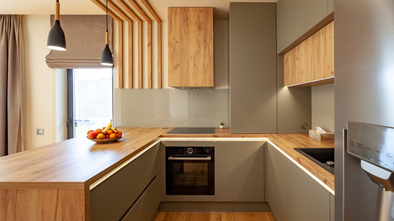 Kitchen with gray walls and light wood cabinets with peninsula