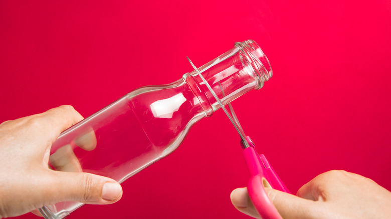 Sharpening scissors on the neck of a glass bottle.