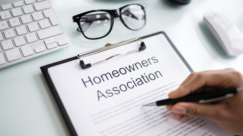 A hand holding a pen over a copy of HOA rules