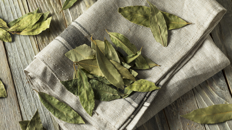 Dried bay leaves on a folded cloth with a wooden background