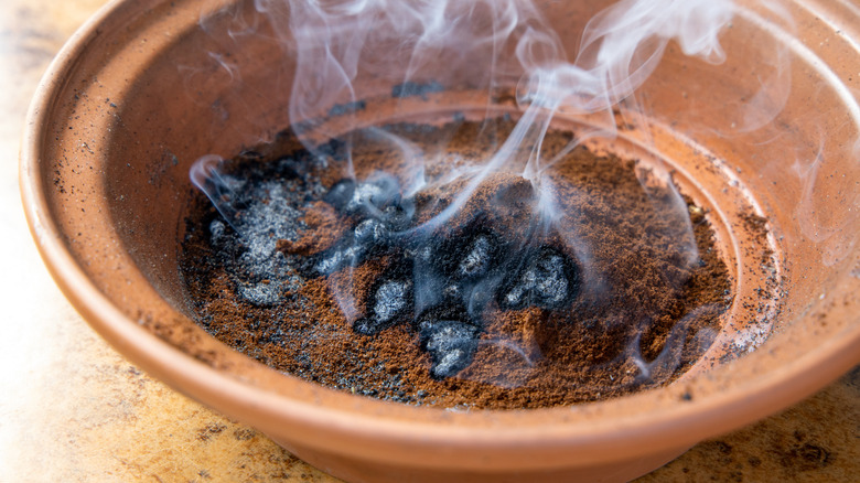 Coffee grounds being burned for mosquito repellent.