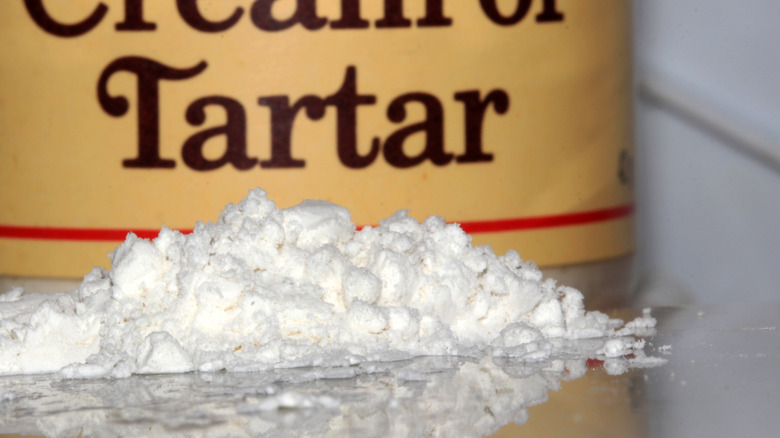 Cream of tartar pile on countertop beside container