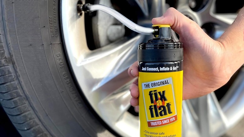 A can of Fix-a-Flat connected to a car tire