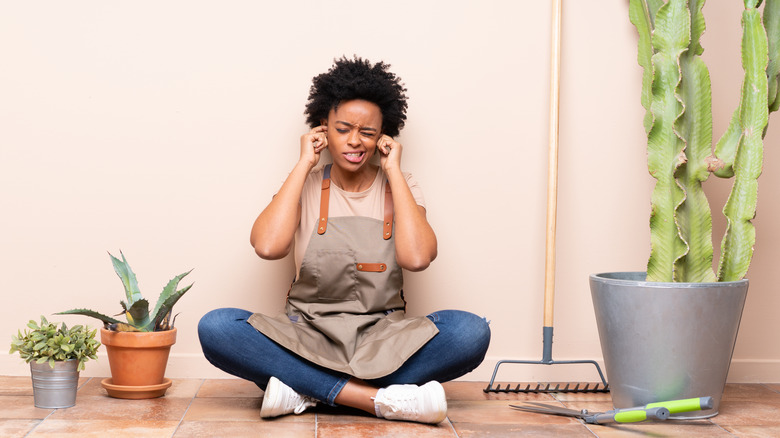 Woman sitting on floor plugging ears 