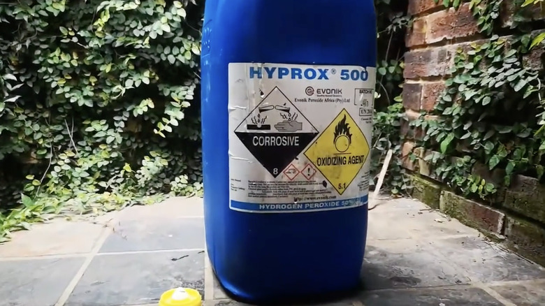 A bottle of 50% concentration hydrogen peroxide on a tiled patio.