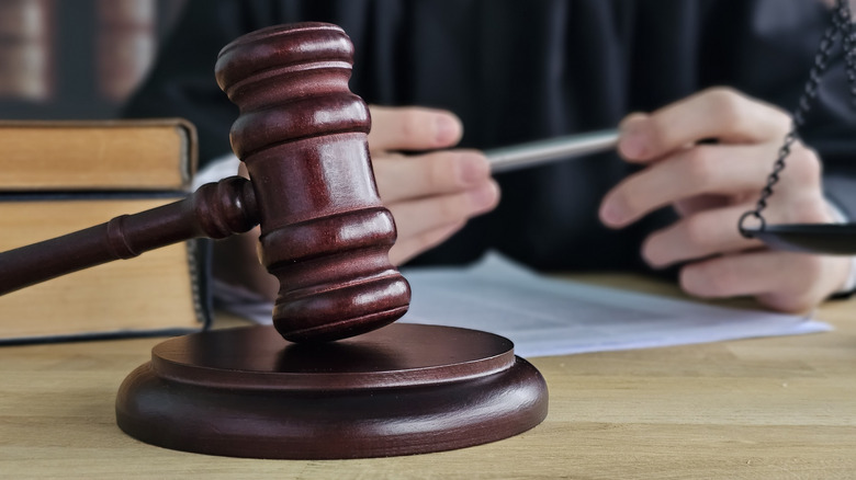 A judge sits at a table with paperwork and a gavel.