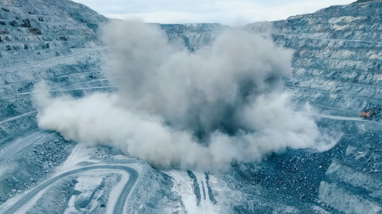 A rock being blasted apart with controlled explosives sending flying debris