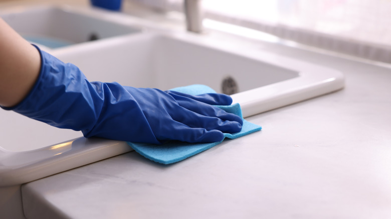 Gloved hand cleans ceramic sink