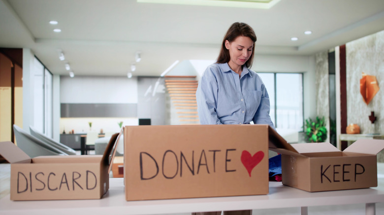 A women decluttering with donation and discard boxes sitting on a kitchen counter