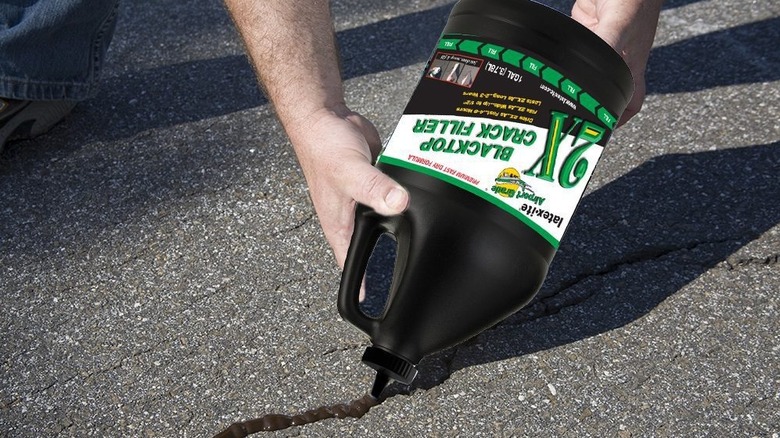 Man's hand holding bottle of Latex-ite crack filler to repair blacktop cracks