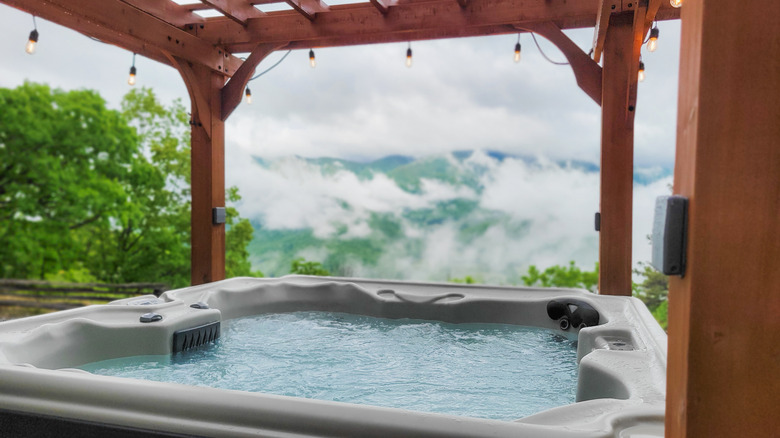 An outdoor hot tub surrounded by trees and mountain views.
