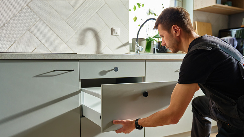 A man opening up his kitchen drawer.